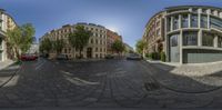 a 360 view of street corner in a city area with tall buildings and vehicles parked on the side