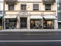 an older store on a city street near some buildings, including a chair, and a table and some chairs