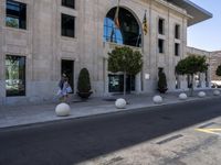 a building next to the street is empty and there are trees around it and shrubs in front are on the street