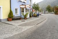 a street scene with a bench and houses on either side of the road where to sit?