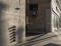 a fire hydrant on the side of a wall near an old building on the corner