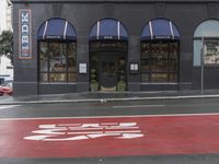 an empty shopping street with store signs painted on the sidewalk in front of it at an intersection