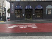 an empty shopping street with store signs painted on the sidewalk in front of it at an intersection