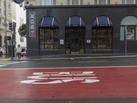 an empty shopping street with store signs painted on the sidewalk in front of it at an intersection