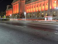 an image of the red light of a building on a street at night in front of it