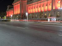 an image of the red light of a building on a street at night in front of it