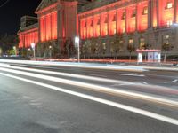 an image of the red light of a building on a street at night in front of it