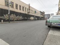a car is parked on the street in front of a building with graffiti on it