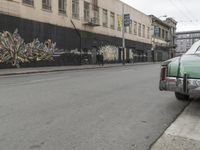 a car is parked on the street in front of a building with graffiti on it