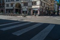 a building sitting next to a crosswalk on the side of street in front of a building with many bicycles parked