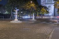 street corner showing a large monument and the eiffel tower in the background at night