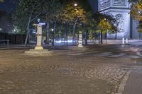 street corner showing a large monument and the eiffel tower in the background at night