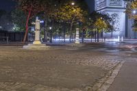 street corner showing a large monument and the eiffel tower in the background at night