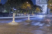 street corner showing a large monument and the eiffel tower in the background at night