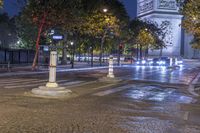 street corner showing a large monument and the eiffel tower in the background at night