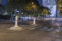 street corner showing a large monument and the eiffel tower in the background at night