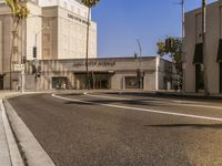 a city street with the sidewalk and palm trees in the background, with a building on the left side