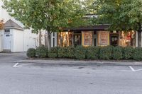 a shop sits in a parking lot near some trees and bushes with signs that say sale