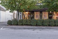 a shop sits in a parking lot near some trees and bushes with signs that say sale