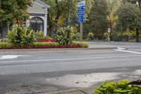 a stop sign in the middle of the street near a planter bed and two blue signs on a pole