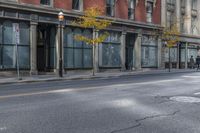 a city street with parked cars and pedestrians walking past stores and buildings on either side of the street