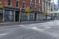 a city street with parked cars and pedestrians walking past stores and buildings on either side of the street