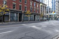 a city street with parked cars and pedestrians walking past stores and buildings on either side of the street