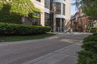 a sidewalk with hedges on the sides and buildings near the street outside of it,