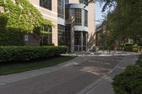 a sidewalk with hedges on the sides and buildings near the street outside of it,