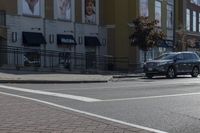 a car stopped at an intersection on a city street, on a clear day with no people