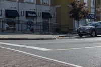 a car stopped at an intersection on a city street, on a clear day with no people