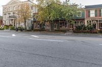 a street with lots of buildings in it with some trees and some grass by the sidewalk