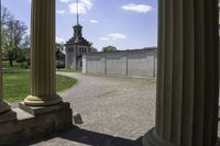 view through some columns of a building with a clock tower in the distance behind it