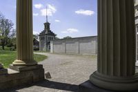 view through some columns of a building with a clock tower in the distance behind it