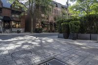 a building with a decorative iron grid pattern on a paved city street with greenery and sidewalk