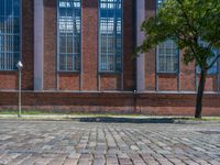 a brick floor sitting outside next to tall windows and a tree on a brick road