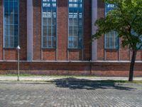 a brick floor sitting outside next to tall windows and a tree on a brick road