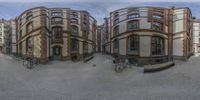 an artistic perspective of a residential building near other buildings and bicycles on the street in front of them