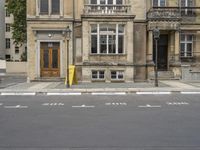 an empty building with signs on the street and people on bikes in traffic passing by