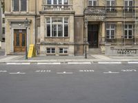 an empty building with signs on the street and people on bikes in traffic passing by