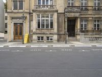 an empty building with signs on the street and people on bikes in traffic passing by