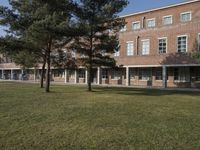 a large brick building on a field with trees in front of it and windows facing the building