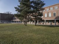 a large brick building on a field with trees in front of it and windows facing the building