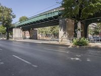 a pedestrian bridge that is over a street filled with vehicles and trees and bushes,