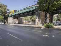 a pedestrian bridge that is over a street filled with vehicles and trees and bushes,