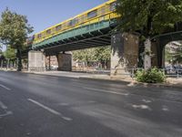 a pedestrian bridge that is over a street filled with vehicles and trees and bushes,