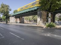 a pedestrian bridge that is over a street filled with vehicles and trees and bushes,