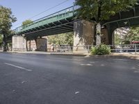 a pedestrian bridge that is over a street filled with vehicles and trees and bushes,