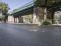 a pedestrian bridge that is over a street filled with vehicles and trees and bushes,