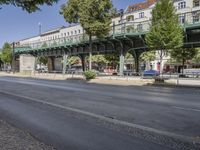 a pedestrian bridge that is over a street filled with vehicles and trees and bushes,